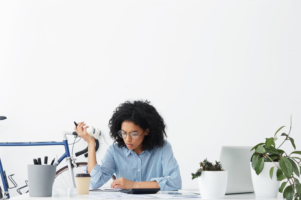 Concentrated young dark-skinned female accountant making report - Dental CPA concentrated young female accountant working